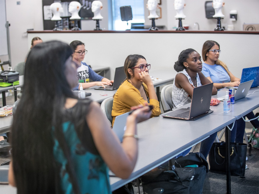 Students in a classroom working on their computers, engaging in collaborative learning and technology-driven education.