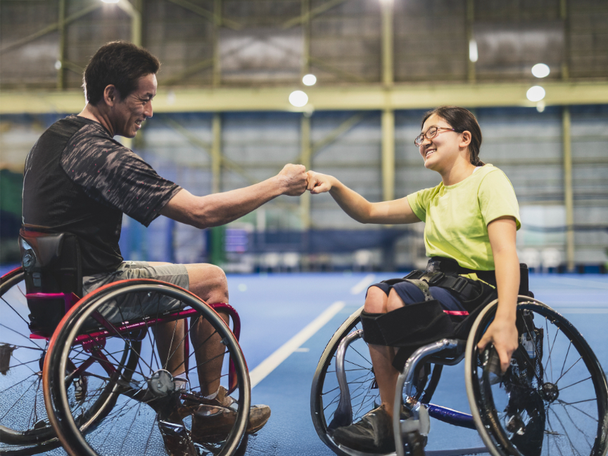 Disabled individuals fist bumping in their wheelchairs, symbolizing strength and camaraderie in the context of the ATSU Masters in Kinesiology program.